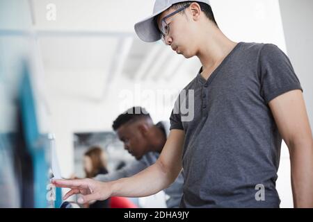 Low angle view of young man doing laundry with friends at laundromat Stock Photo