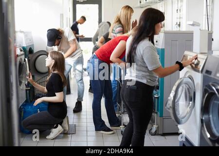 Multi-ethnic university students doing laundry at laundromat Stock Photo