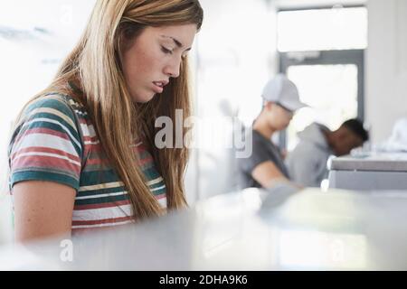 Young woman doing laundry at laundromat Stock Photo