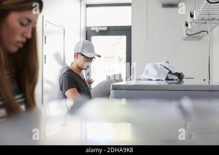 Young man with university friends doing laundry at laundromat Stock Photo