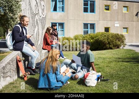 University students talking while sitting at campus Stock Photo
