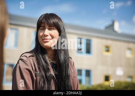 Smiling young woman with long black hair at university campus Stock Photo