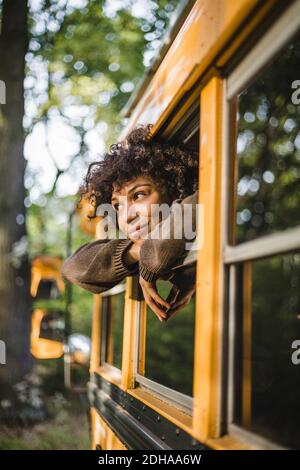 Thoughtful young woman looking through caravan window during camping in forest Stock Photo