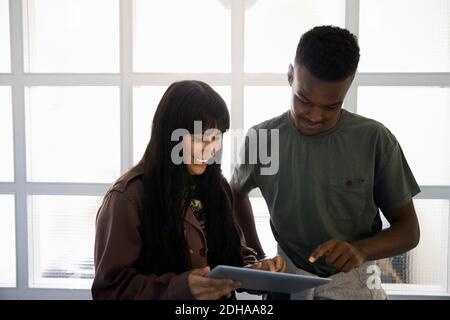 Smiling friends using digital tablet while standing at university Stock Photo