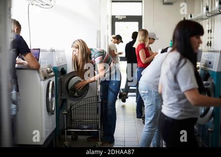 Multi-ethnic university students using washing machines in laundromat Stock Photo