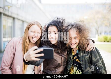 Happy teenage girl taking selfie with friends from smart phone Stock Photo