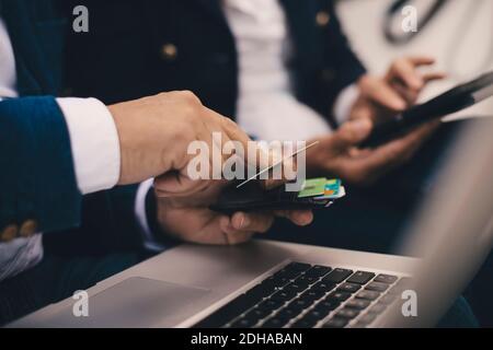 Cropped image of senior man holding credit card while doing online shopping in yacht Stock Photo