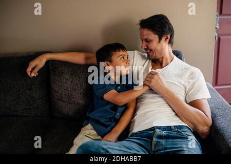 Happy father with son sitting on sofa at home Stock Photo
