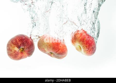 Bunch of doughnut peaches isolated on white, splashing into water. Stock Photo