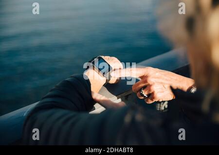 Cropped image of senior woman using smart watch at bridge railing Stock Photo