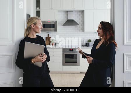 Female colleagues discussing at doorway in home office Stock Photo