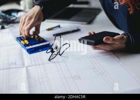 Midsection of female engineer holding portable hard drive on desk Stock Photo