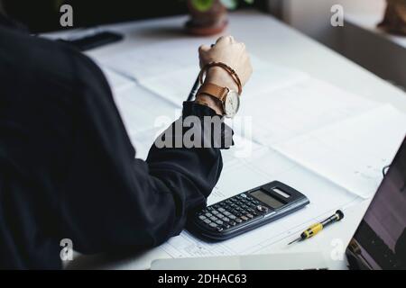 Cropped image of female engineer with blueprint and calculator on desk Stock Photo