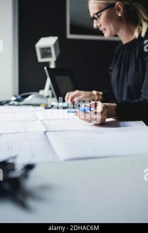 Female engineer holding pen while using calculator on desk at home office Stock Photo