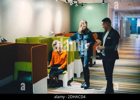 Smiling multi-ethnic business colleagues talking in corridor at office Stock Photo