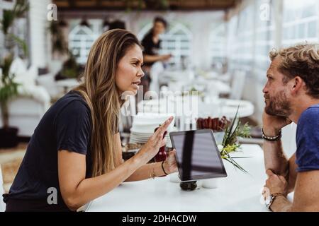 Female owner taking order from customer while using digital tablet in restaurant Stock Photo