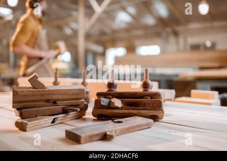 Workbench with old vintage carpentry tools and carpenter on the background in the shop Stock Photo
