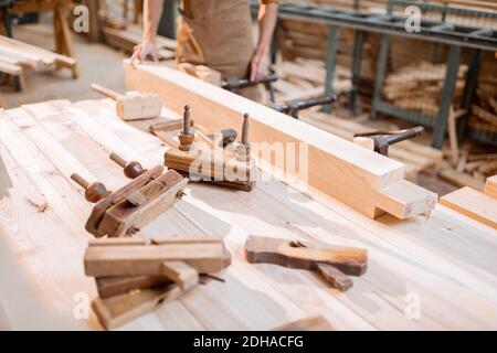 Workbench with old vintage carpentry tools and carpenter on the background in the shop Stock Photo