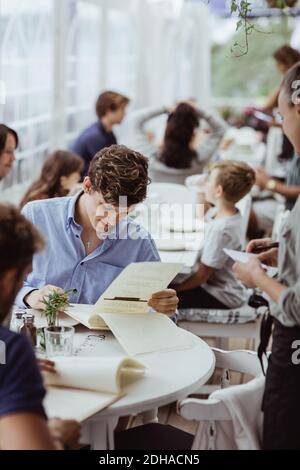 Female owner taking order from male customer sitting in restaurant Stock Photo