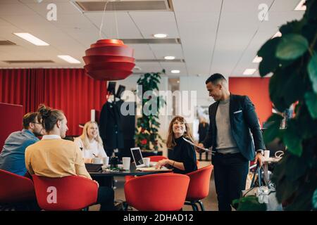 Smiling colleagues looking at businessman standing with bag and documents at office Stock Photo
