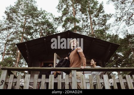 Low angle view of smiling friends standing at porch against house Stock Photo
