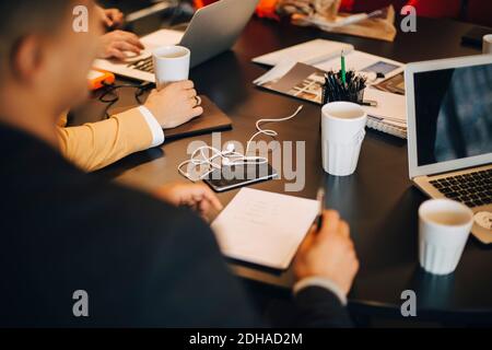 Cropped image of businessman sitting with documents at conference table in office Stock Photo