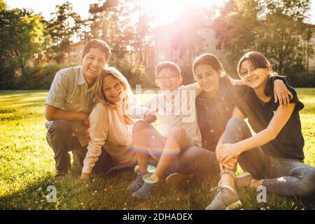 Portrait of smiling family sitting on grassy field at park Stock Photo