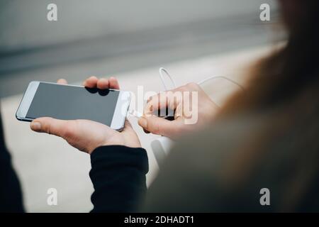 Cropped image of mature businesswoman inserting USB cable in smart phone Stock Photo