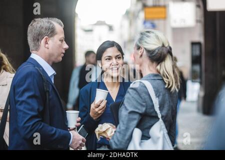 Mature business people standing with smiling coworker in city Stock Photo