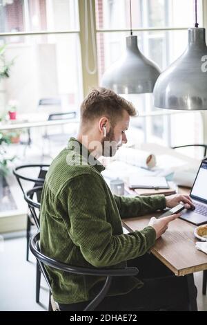 Male entrepreneur using laptop and phone while sitting at home Stock Photo