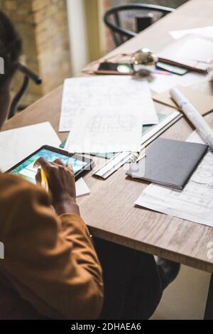 High angle view of female designer using digital tablet while sitting by desk at home office Stock Photo
