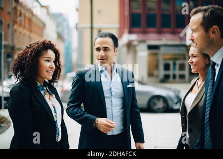 Smiling business colleagues talking while standing in city Stock Photo