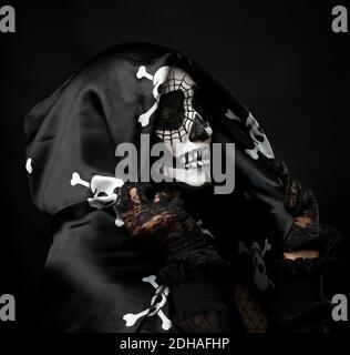 Portrait of a woman in a make-up of a skeleton dressed in a black cloak with a cap Stock Photo