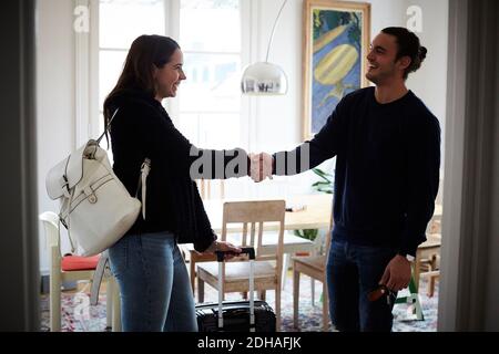 Smiling man and woman shaking hands while standing in apartment Stock Photo