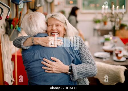 Happy senior woman embracing man while standing at home Stock Photo