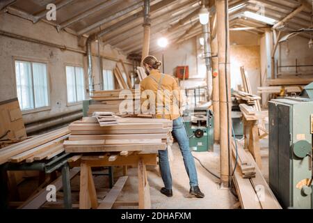 Carpenter choosing pine planks in a carpentry workshop warehouse. Preparing raw materials for the future woodwork Stock Photo