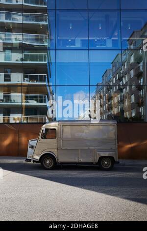 Food truck parked on city street against modern glass building Stock Photo