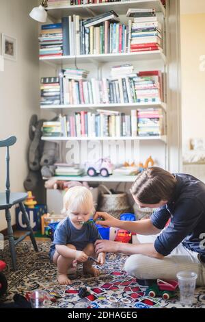 Man brushing toddler's teeth while playing in living room at home Stock Photo