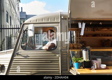 Portrait of smiling salesman sitting in food truck Stock Photo