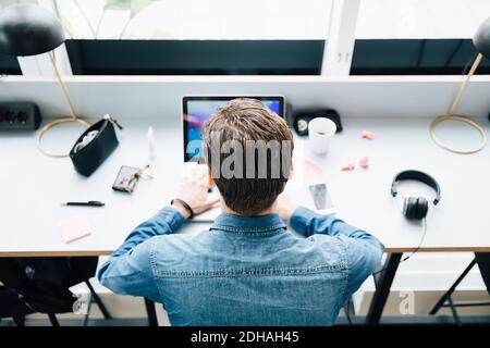 High angle view of businessman using laptop while sitting at desk in office Stock Photo