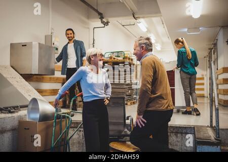 Mature businessman and businesswoman talking while moving into new office Stock Photo