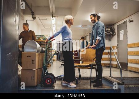 Businessman and businesswoman talking while moving into new office Stock Photo