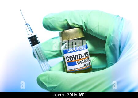 Hand im Latexhandschuh hält Injektionsfläschchen mit Corona-Impfstoff und Impfspritze, Symbolfoto Corona-Impfmittel