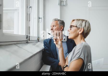 Business people looking through window while discussing in new office Stock Photo