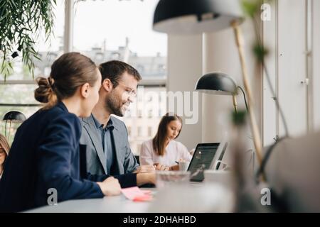 Creative professionals discussing over laptop at desk in coworking space Stock Photo