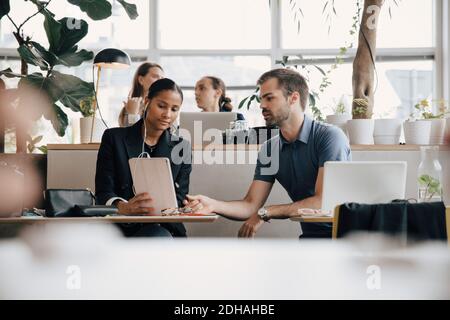 Creative professionals discussing over digital tablet at office desk Stock Photo