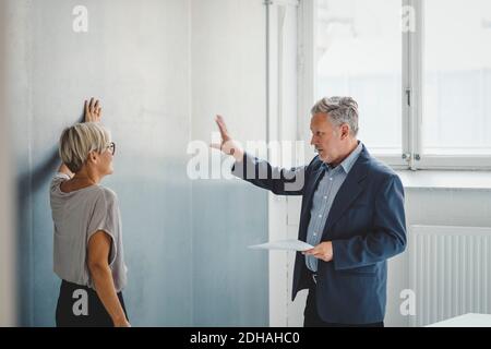 Mature businessman holding documents while discussing with female colleague in new office Stock Photo