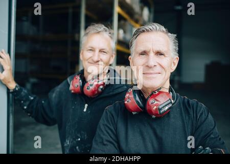 Portrait of smiling workers standing in entrance at industry Stock Photo