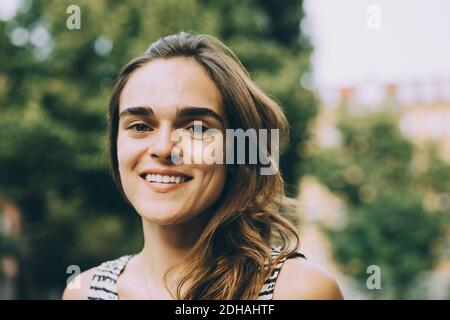 Close-up portrait of smiling young woman with brown hair Stock Photo