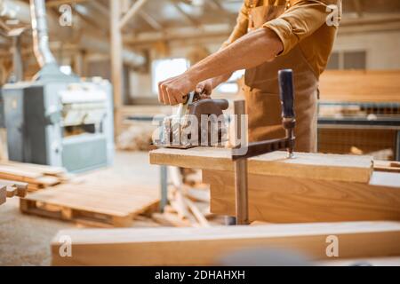 Carpenter sawing wooden bars with cordless electric saw at the joiner's workshop Stock Photo